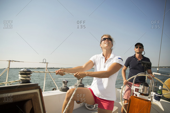 Woman adjusting rope on yacht with friends