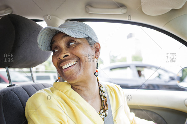 Older woman in driver\'s seat of car looking behind her