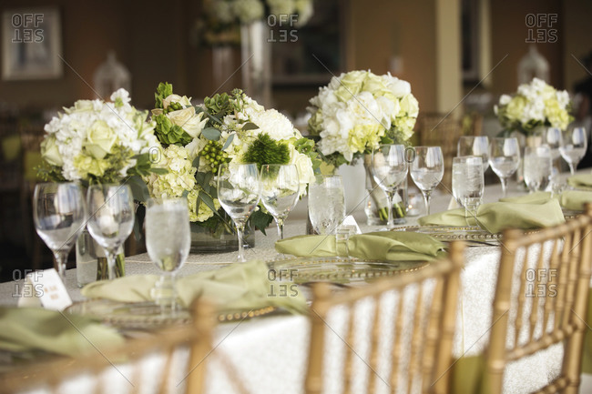 A table set with light green flowers for a bridal party