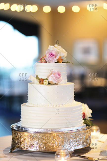 A white wedding cake on a silver cake stand