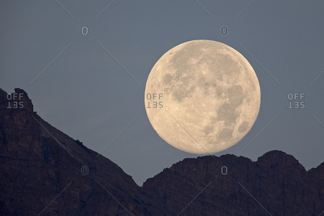 Full moon above a mountain in Glacier National Park, Montana, USA