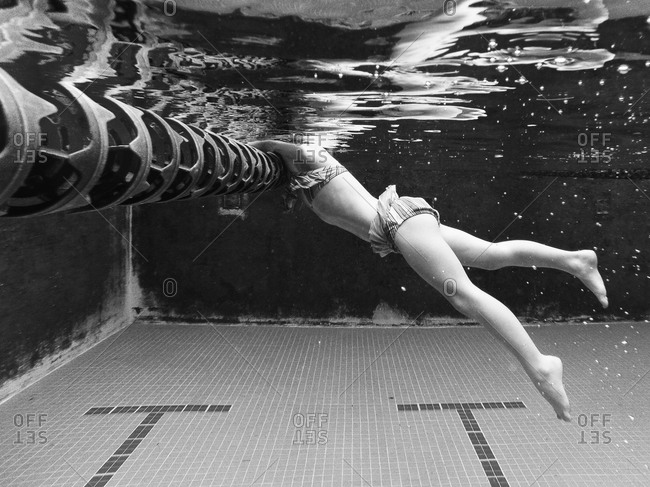Underwater view of child holding onto swim lane rope