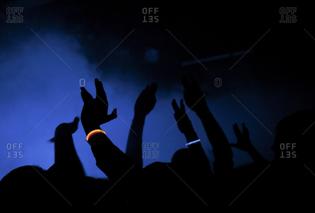 People at a concert raise up their arms