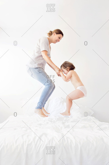 A mom and her daughter jump on a bed