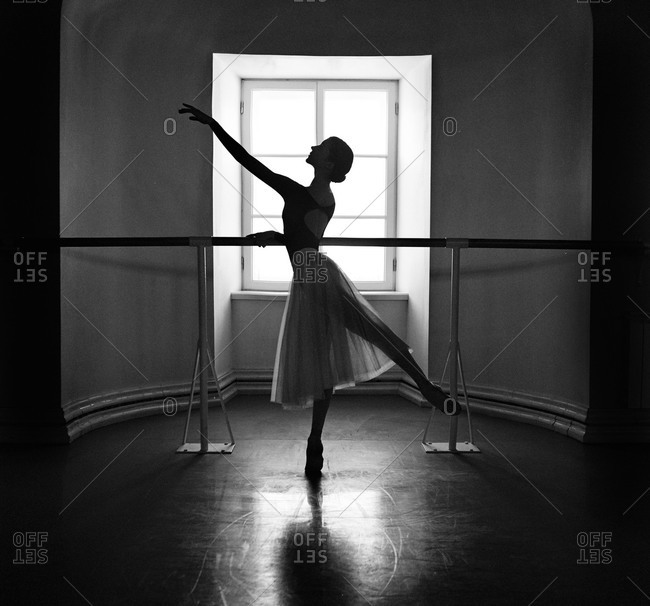 Female ballet dancer at barre in front of window