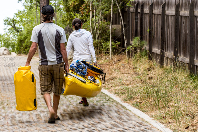 Two people carrying kayak and gear