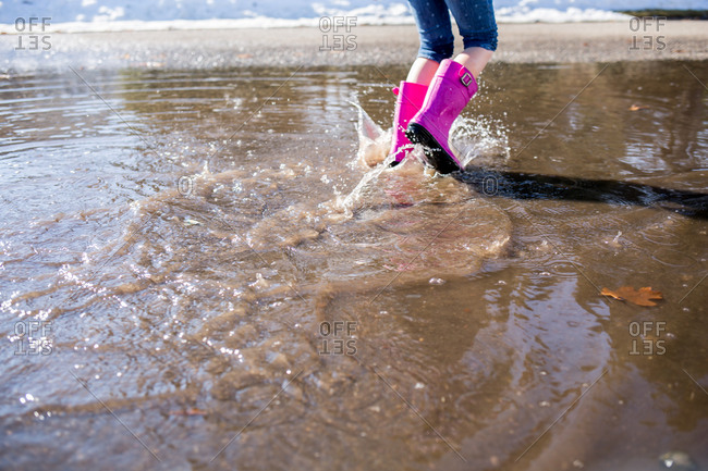 Girl walking through a puddle with pink boots