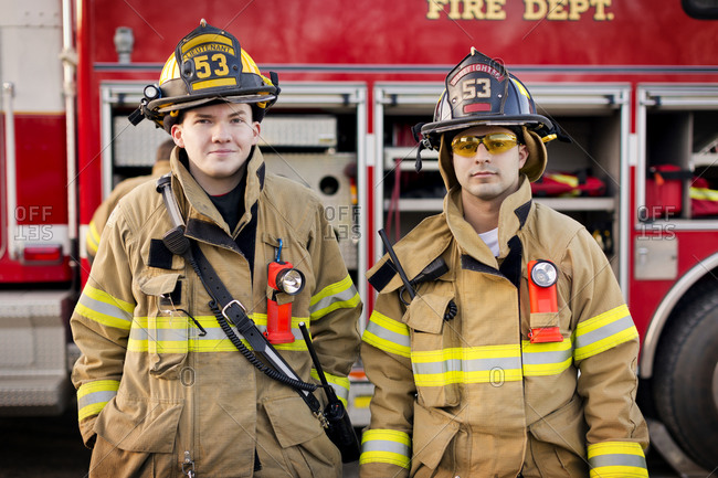 Two firefighters standing in front of a fire engine