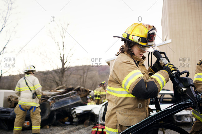 A firewoman using the jaws of life to break into a car