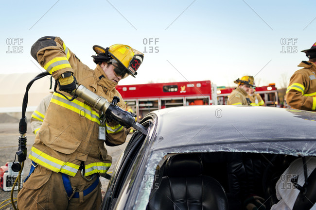 A fireman using the jaws of life to break into a car