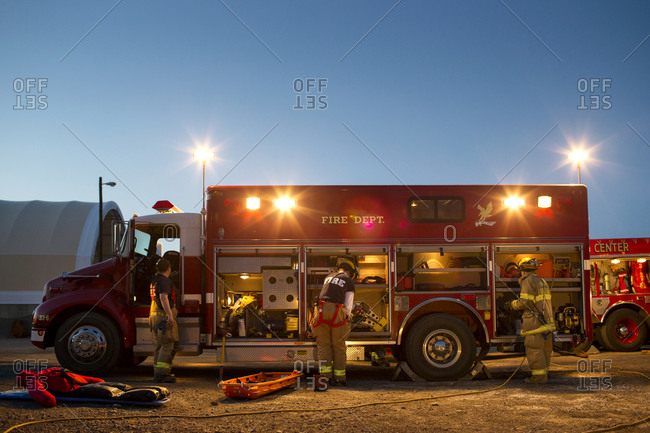 Firemen load up their fire truck at dusk