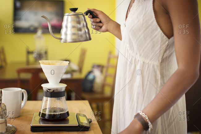 A woman makes coffee using a pour over coffee maker