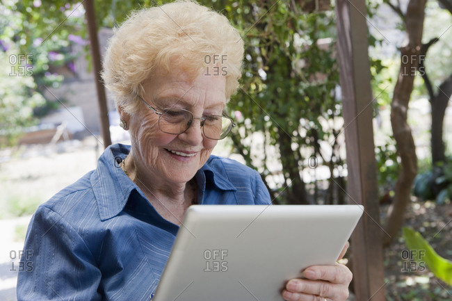 Elderly woman using tablet computer outdoors