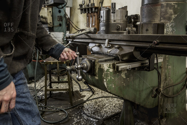 Worker using machinery in metal shop