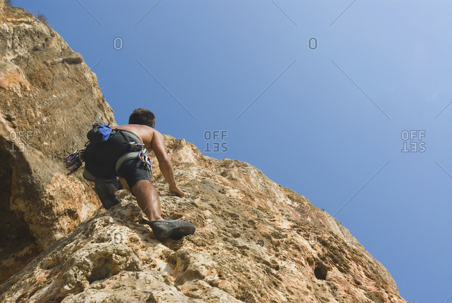 Low angle view of man scaling rock face
