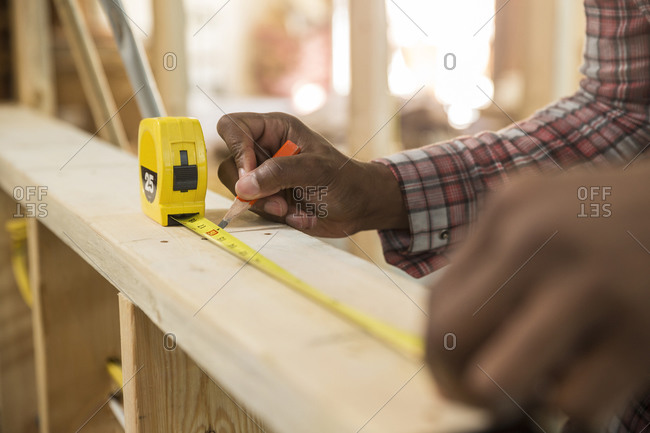 Worker measuring wood at construction site