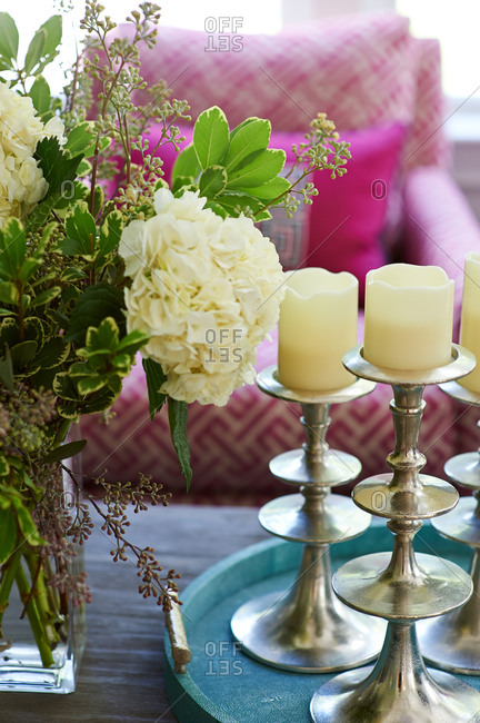 Table with white flower arrangement and candles with purple chair in background