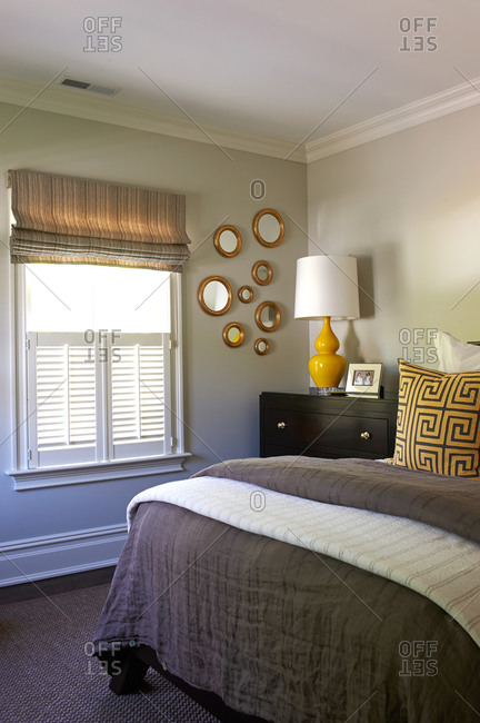 A gray bedroom with yellow accents and gold circle mirrors on the wall