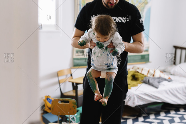 Father lifting up toddler covered in green paint