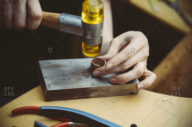 Goldsmith working with rubber mallet on wedding rings