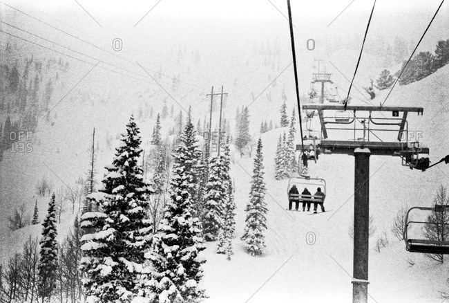 People riding ski lift up snowy slope