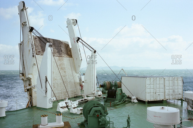 Heavy machinery and shipping containers on the top of a boat