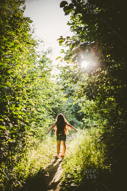 Back view of girl on a wooded path in the sun