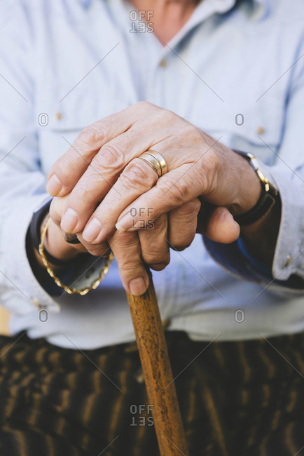 Close-up of old man\'s hands resting on a cane