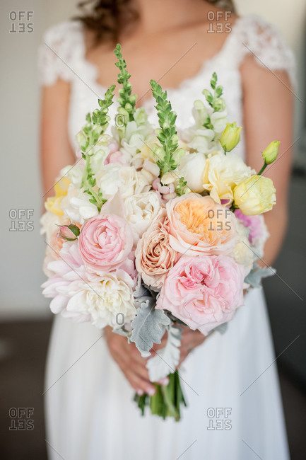 Bride holding her bouquet of white, pink, and yellow flowers