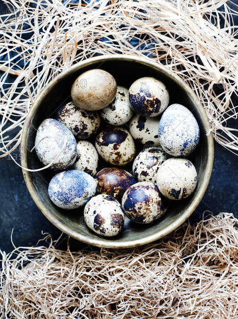 Quail eggs in a rustic copper bowl