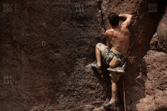 Shirtless man climbing on a cliff in Pinnacles National Monument, USA