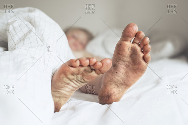 Child\'s dirty feet in bed