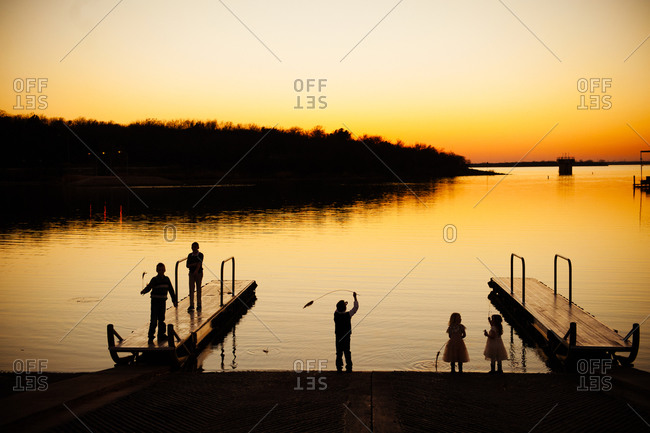 Silhouette of children playing in harbor at sunset