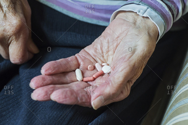Mid-section of senior woman holding pills while sitting at home