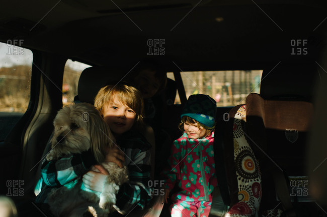 Children sitting in a car with a dog