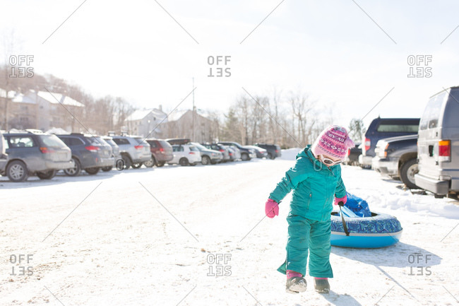Girl pulling sled in snowy parking lot