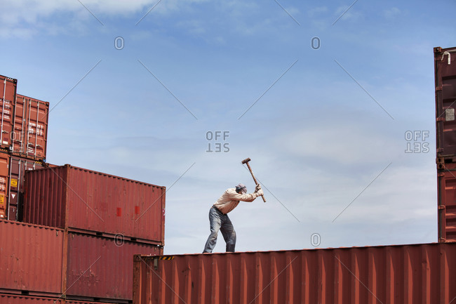 Man using sledgehammer on freight container