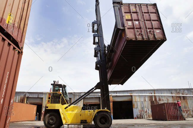 Forklift in freight shipping yard moving cargo