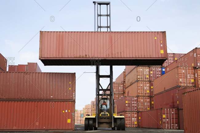 Forklift in freight shipping yard moving containers