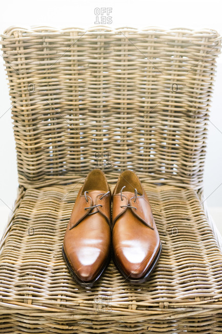 Brown dress shoes on a rattan chair