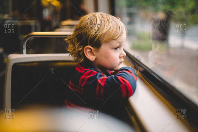 Little boy staring out the window of a train