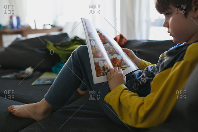 Young boy reading a graphic novel on a couch