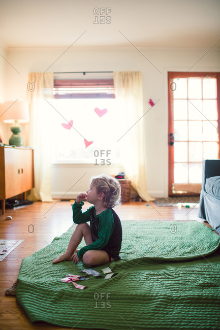 A little boy watches television while sitting on a green blanket