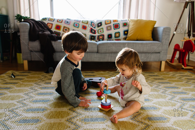 A little boy helps his sister with a stacking toy