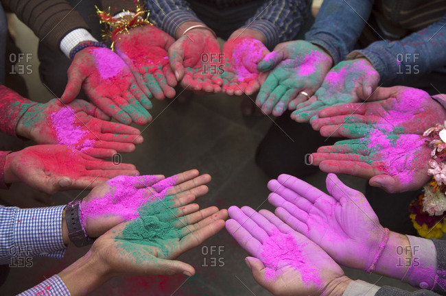 People holding colorful powdered paint in their palms during Holi festival in Mathura, India