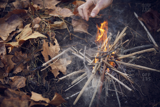 Close up of man starting campfire with kindling
