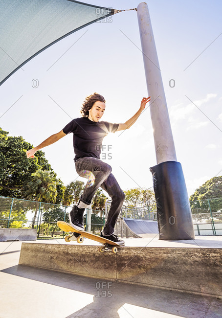 Skateboarder grinding on low wall