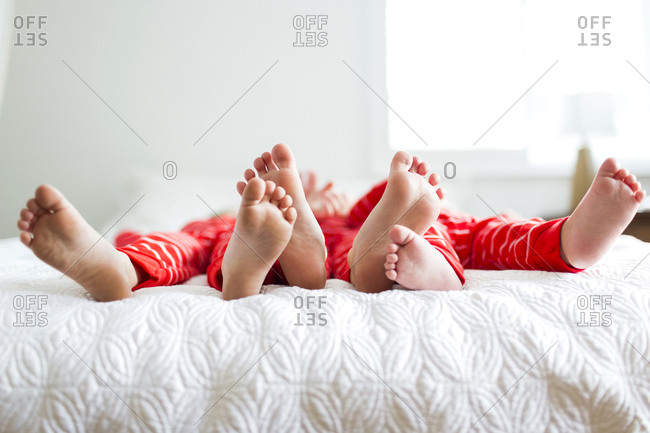 Siblings in red pajamas lying on bed