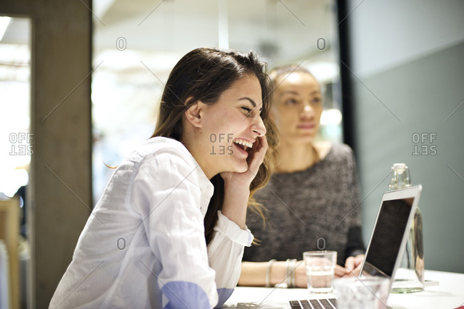 Young woman laughs while in meeting with co-workers