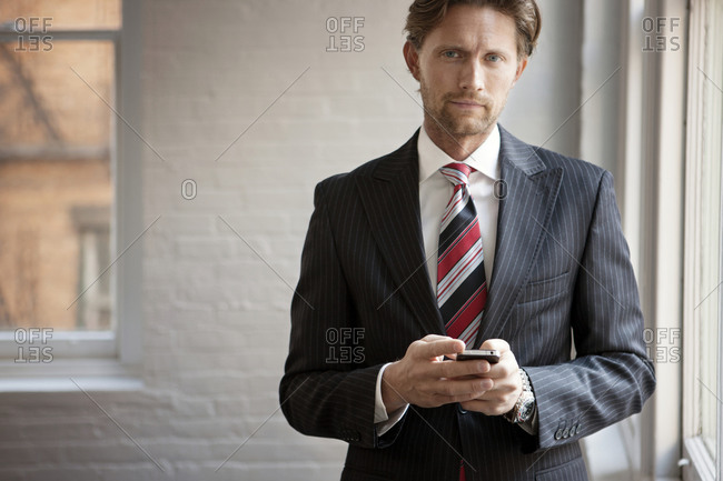 A man in a pinstripe suit holds his phone